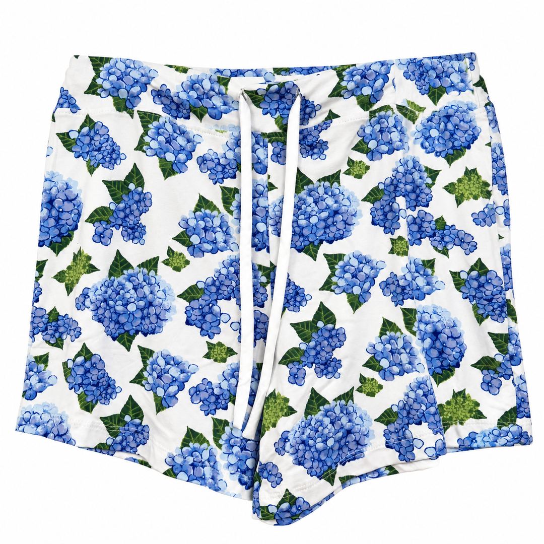 White shorts featuring a blue and green hydrangea floral print, complete with a white drawstring waist.