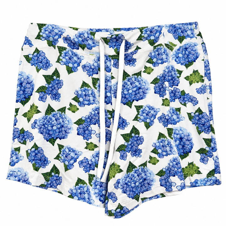 White shorts featuring a blue and green hydrangea floral print, complete with a white drawstring waist.