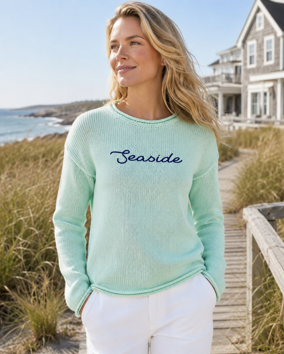 Woman wearing a light green sweater with 'Seaside' text on a beach